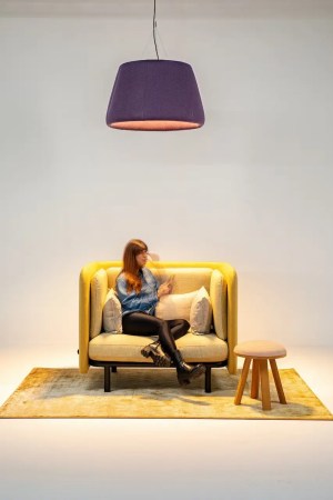 La lampe suspendue acoustique design violet de Buzzispace qui éclaire une fauteuil acoustique confortable dans un espace de travail et de détente