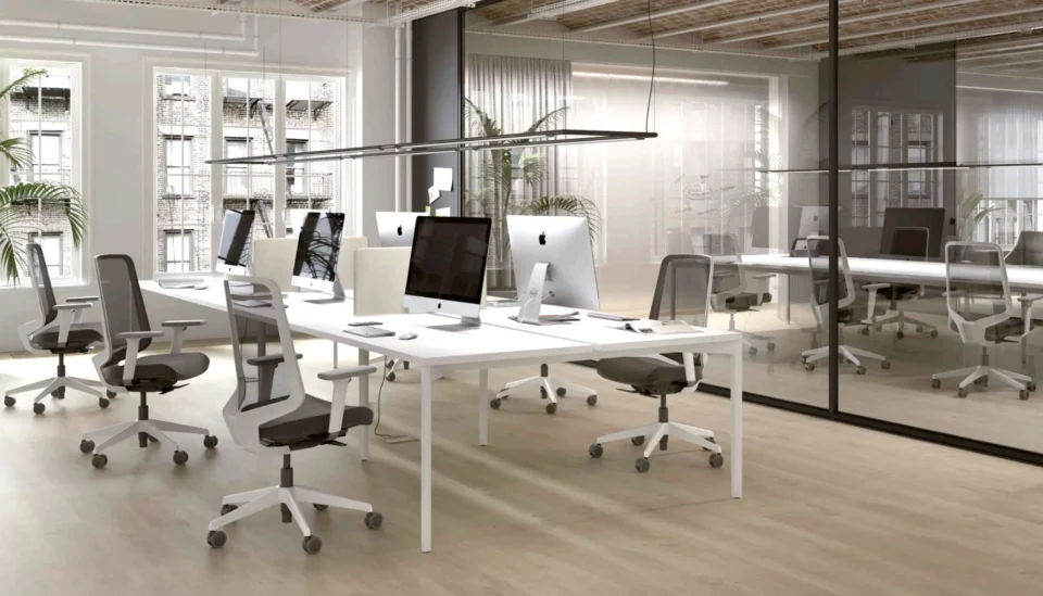 Un bureau moderne avec des bureaux blancs et des murs en verre. Bureau bench chaise ergonomique.