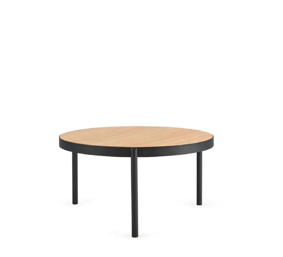 Une table ronde gigogne avec des pieds noirs et un plateau en bois. Près d'elle se trouve un fauteuil lounge.