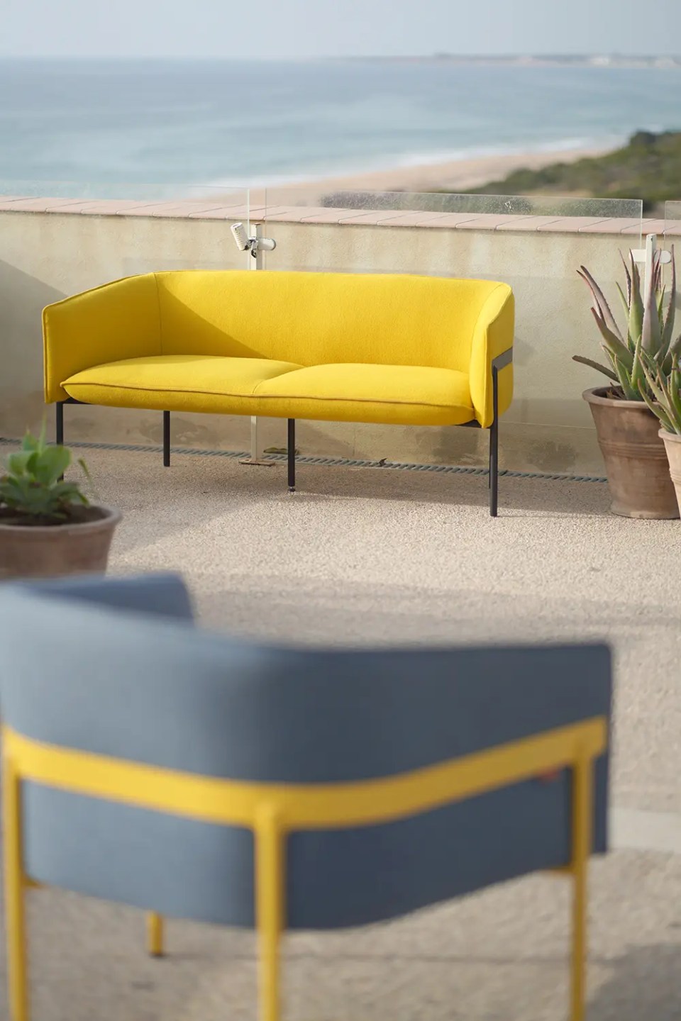 Une chauffeuse lounge jaune et grise sur une terrasse.