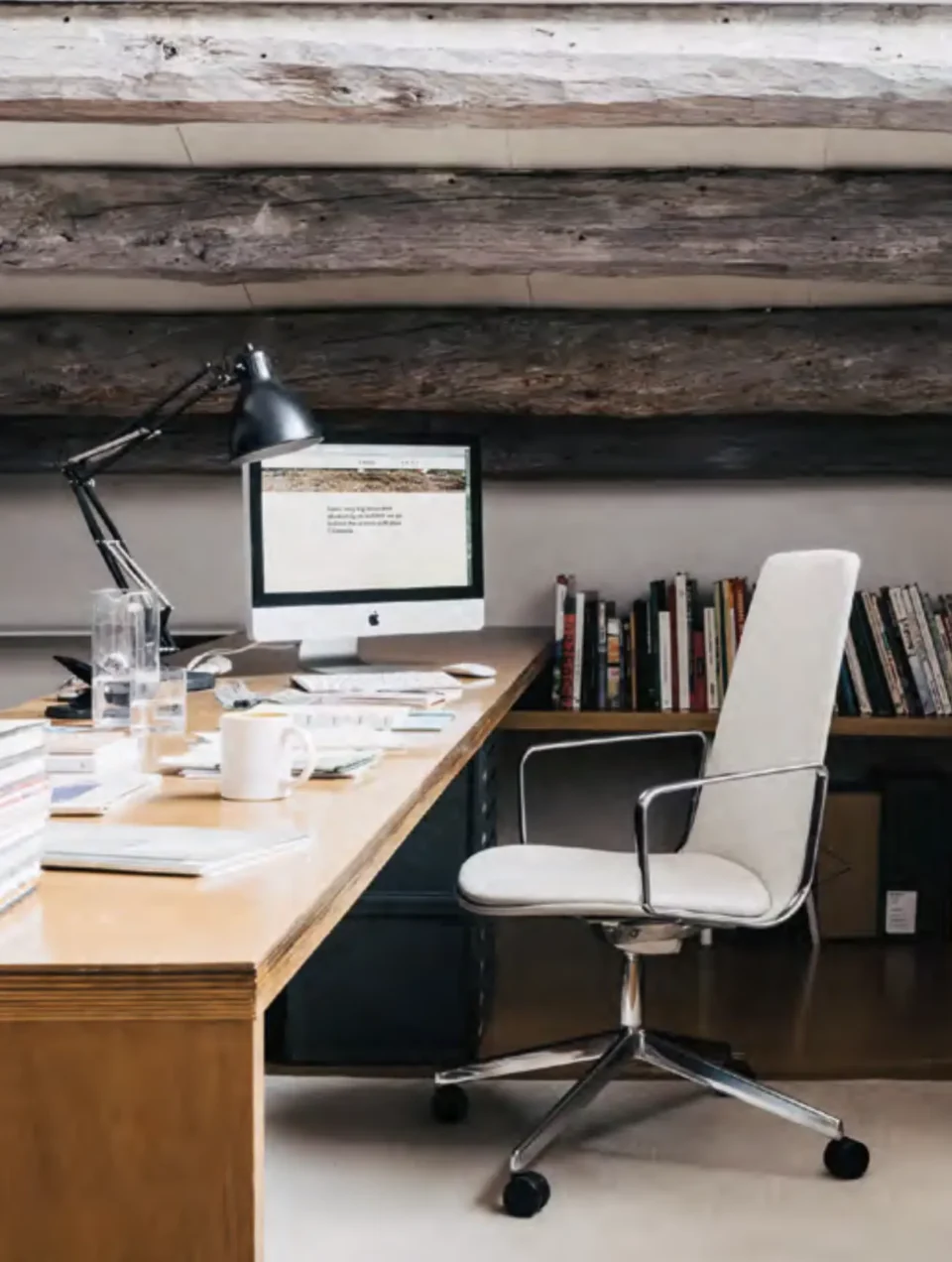 fauteuil de direction blanc chromé a roulettes derriere un bureau ergonmique